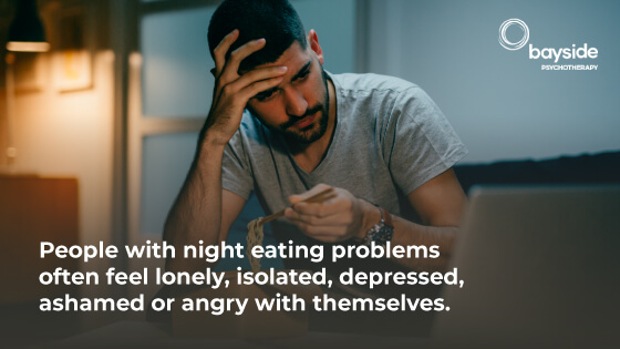 man with black hair holding his head with his head while eating pasta and looking worried and a quote about night eating syndrome