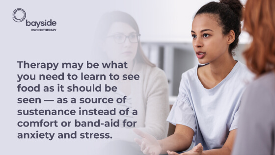 women with black hair wearing a light blue T-shirt explaining something to other women and a quote about therapy and food