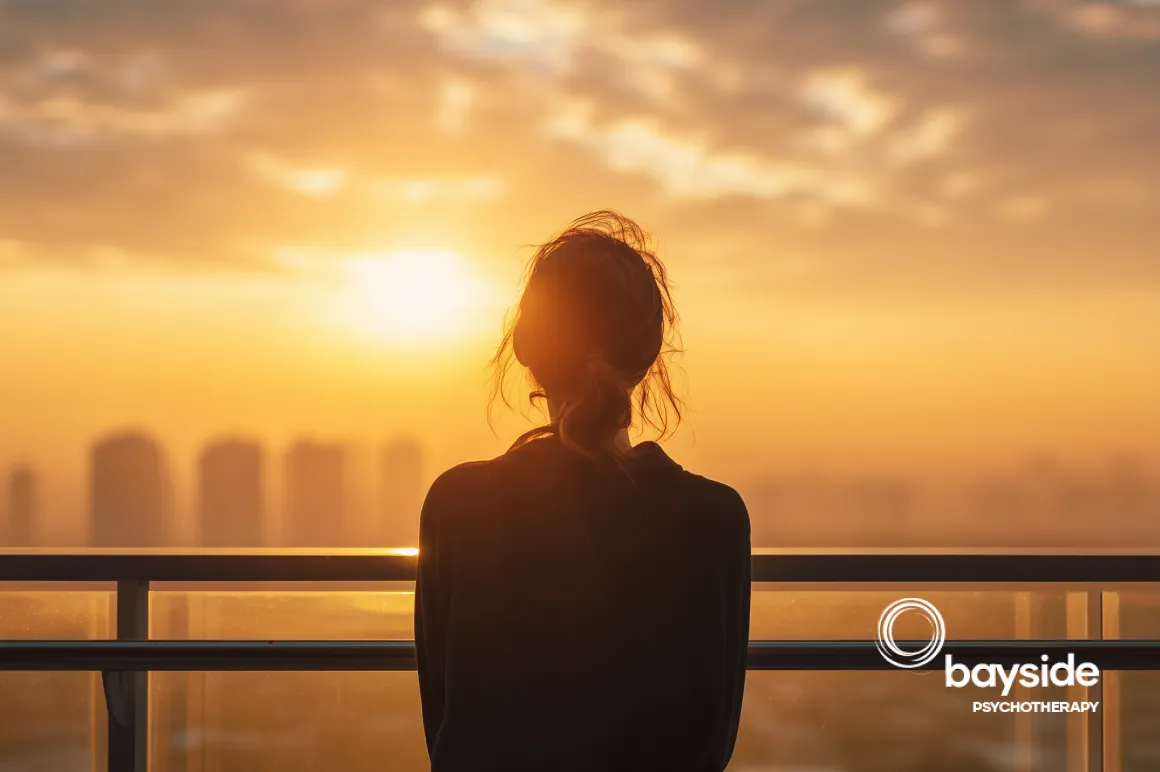 couple in backlight during sunset, viewed from the back and semi-profile discussing with the Bayside Psychotherapy logo on the right side