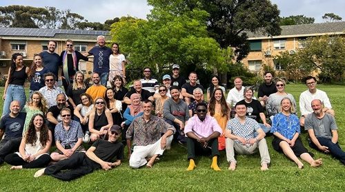 Community Group Gathering Outdoors Group photo of diverse individuals gathered on a lawn in front of residential buildings, smiling and relaxed in an outdoor setting.